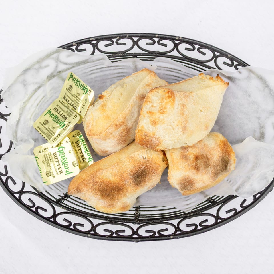 Basket of toasted bread slices served with individually wrapped butter packets.