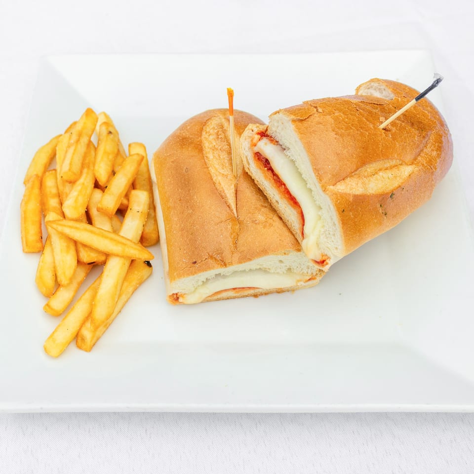 Toasted baguette sandwich with melted cheese and tomato sauce, served with golden French fries on a white plate.